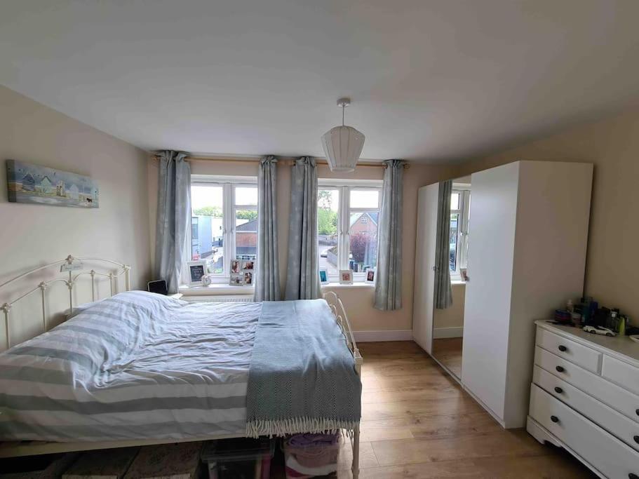 um quarto com uma cama, uma cómoda e janelas em Large Luxury appartment em Cobham