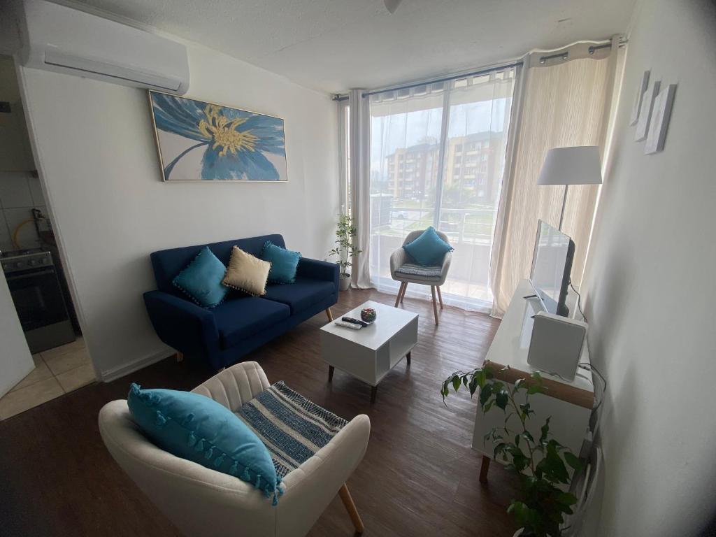 a living room with a blue couch and a table at Apartamento altos del boldo in Curicó