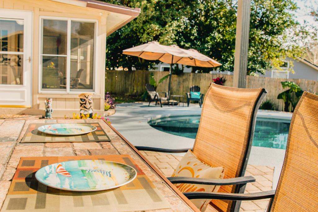 a patio with a table with two chairs and a pool at Sun & Fun 3BR Beach Home with Pool & Tiki Bar in Jacksonville