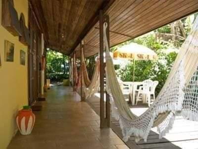 a porch with hammocks and a table and chairs at Pousada Tia Tina in Paranaguá