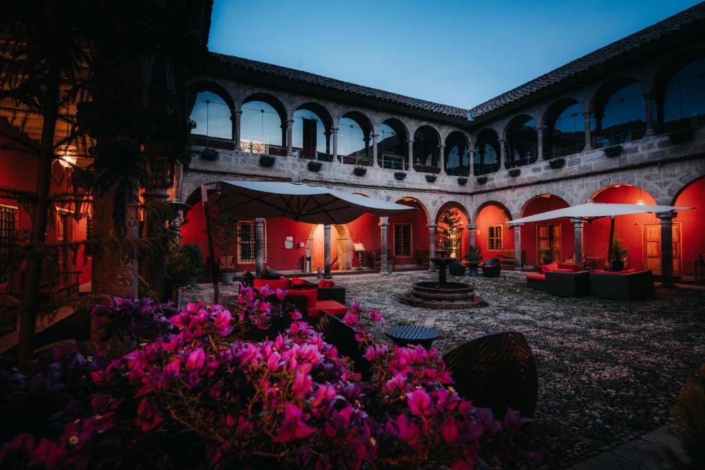 une cour avec des fleurs roses dans un bâtiment dans l'établissement Costa del Sol Wyndham Cusco, à Cusco