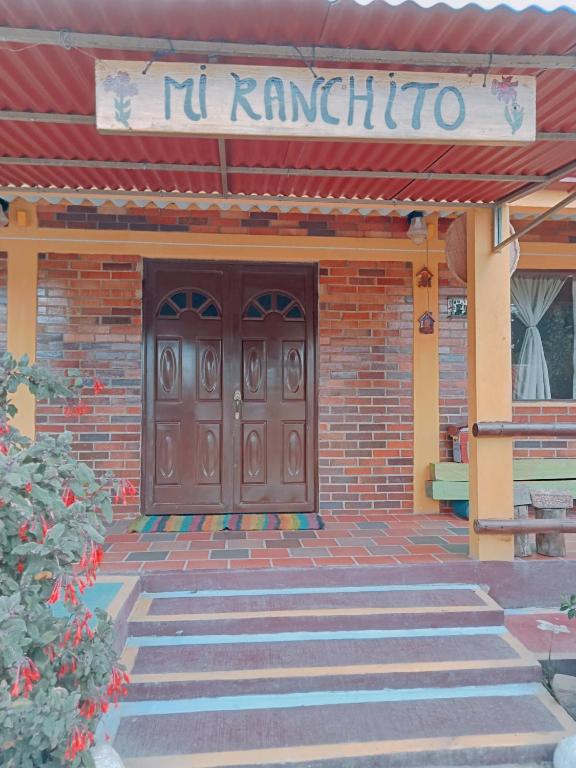 un bâtiment avec une porte marron et un panneau sur celui-ci dans l'établissement MI RANCHITO, à Sogamoso