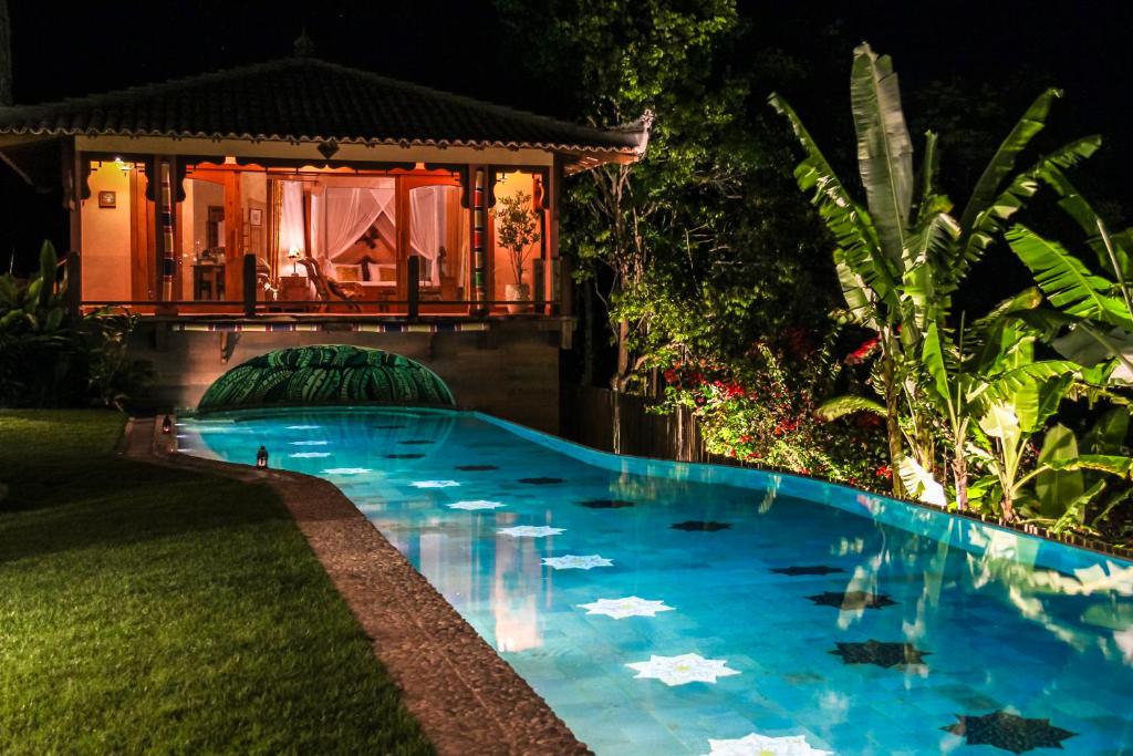 a swimming pool in front of a house at night at Sagui Boutique Hotel in Arraial d'Ajuda