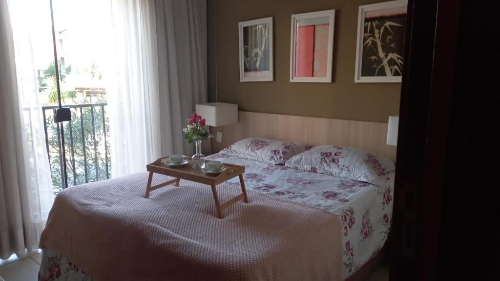 Un dormitorio con una cama y una mesa con flores. en Lindo Flat no Aldeias das Águas en Barra do Piraí