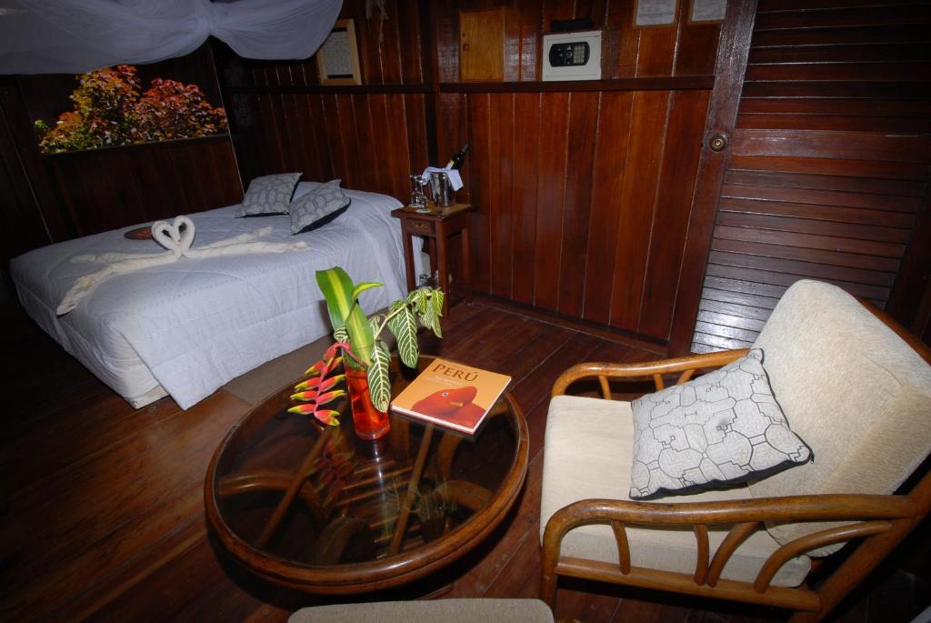 1 dormitorio con 1 cama, mesa y sillas en Sandoval Lake Lodge, en Puerto Maldonado