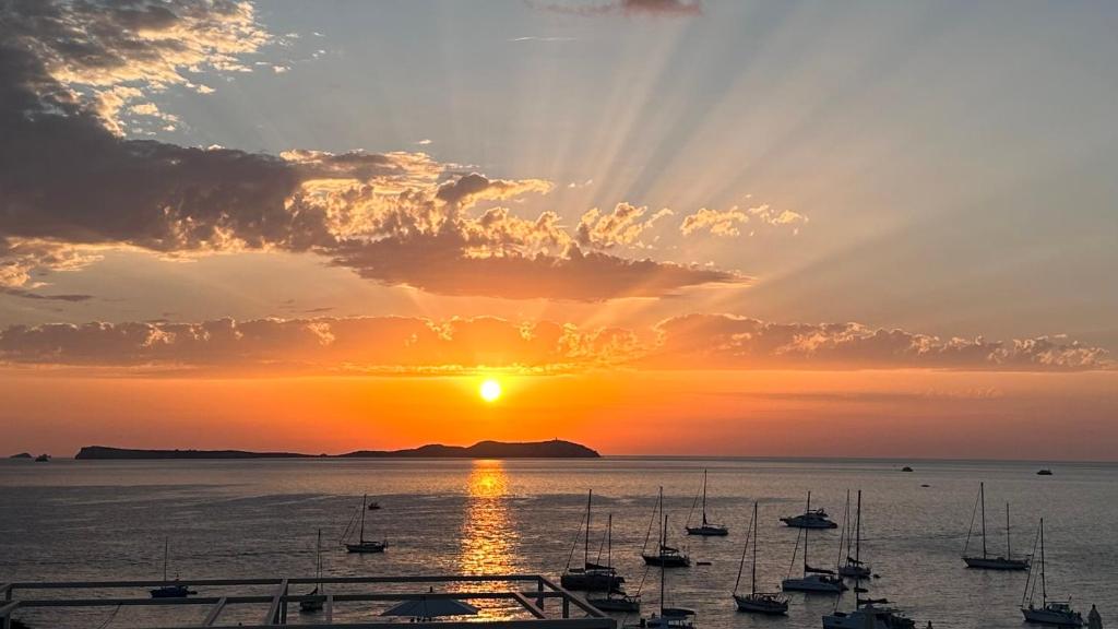 a sunset over a body of water with boats at Aparthotel Boutique Poniente Playa in San Antonio