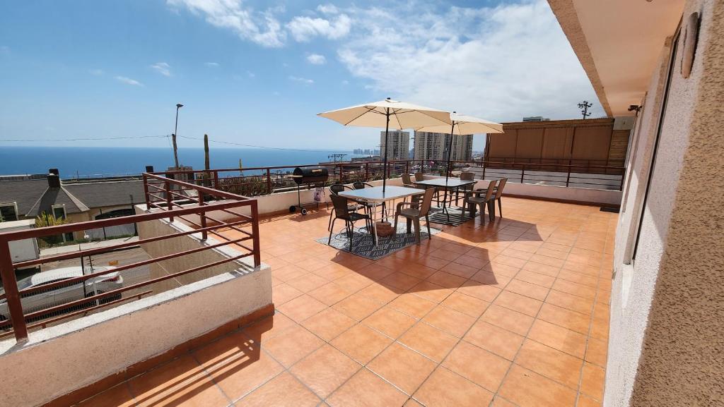 a balcony with a table and chairs and an umbrella at Hermoso Departamento Iquique in Iquique