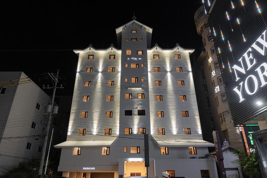 un edificio blanco alto con una torre por la noche en Cheonan Aank Hotel Seongjeong en Cheonan