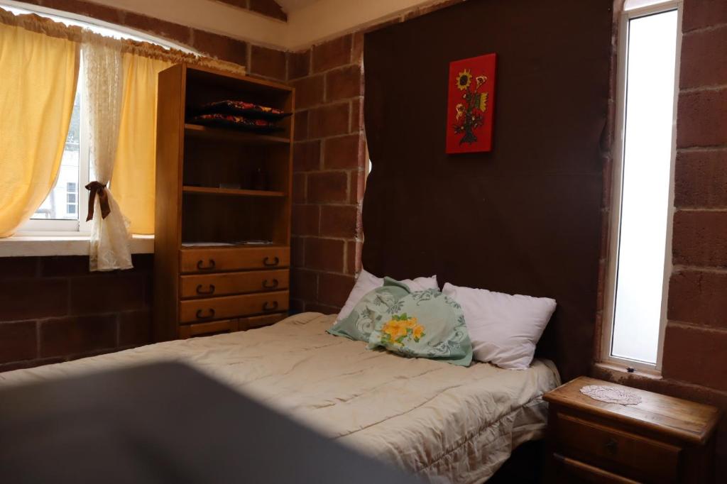 een slaapkamer met een bed met 2 kussens erop bij KOLSA in Santa María Tonantzintla