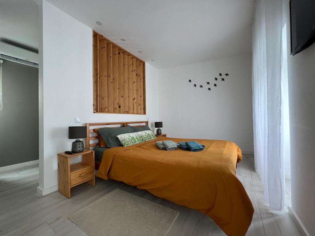 a bedroom with a bed with an orange blanket at Urban 44 Guest House in Ponta Delgada