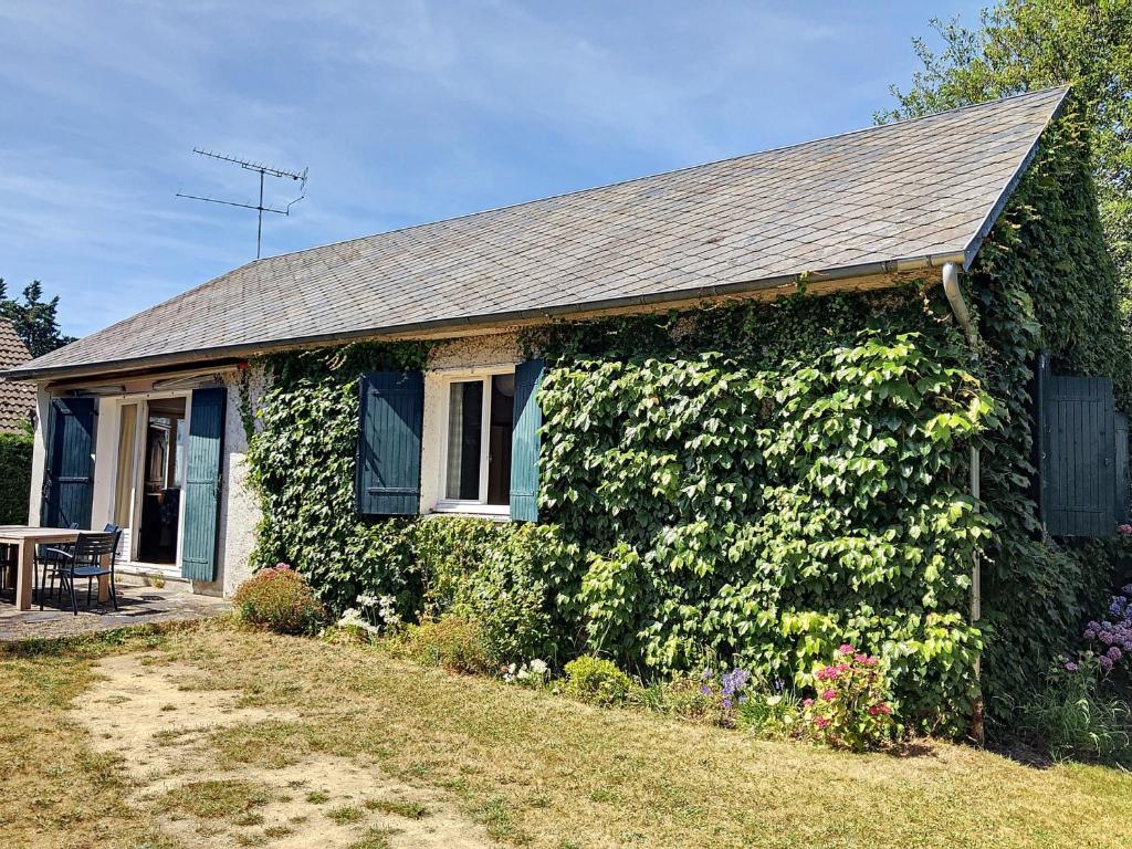 une maison recouverte de lierre vert à côté d'une cour dans l'établissement Maison Plain-Pied avec Jardin, 500m Plage, 3 Ch, 6 Pers, WiFi, Stationnement, Proche Mont-Saint-Michel - FR-1-361-160, à Jullouville