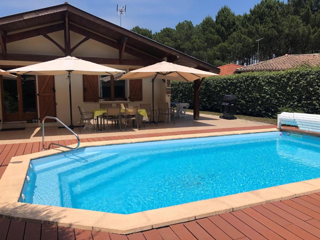 una piscina con sombrillas junto a una casa en Villa Messanges, 5 pièces, 8 personnes - FR-1-239-629, en Messanges