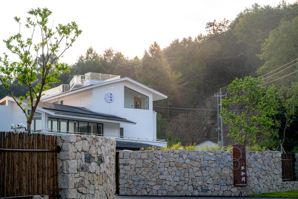 een wit huis achter een stenen hek bij Brandy Manor Wild Luxury B&B - Jinzhai Branch in Jinzhai