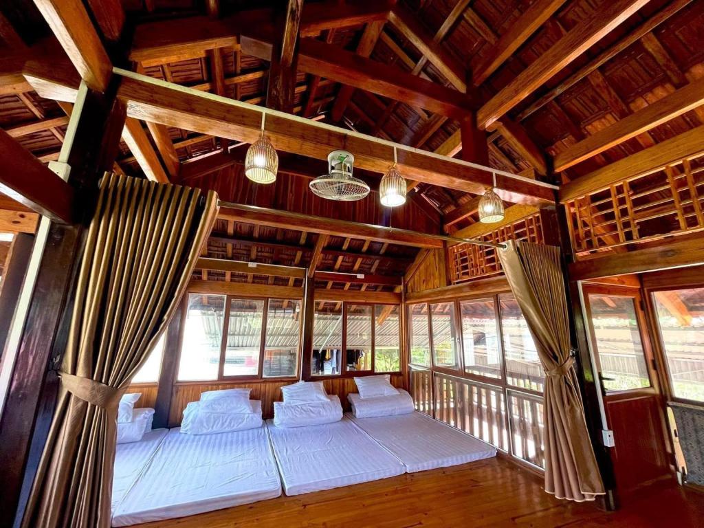 - une chambre avec des lits blancs dans une pièce avec des fenêtres dans l'établissement Cao nguyên, à Mộc Châu