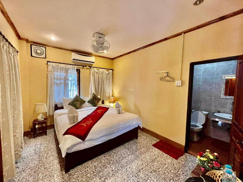a bedroom with a large bed and a bathroom at Luang Prabang Rosie Place in Luang Prabang