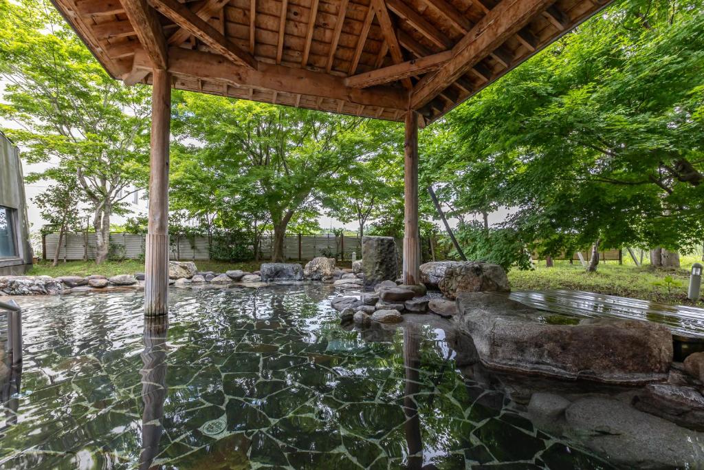 a backyard with a pond with rocks and a wooden roof at KAMENOI HOTEL Aomori Makado in Noheji