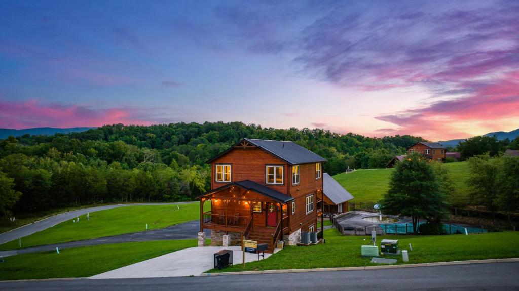 a house on a hill with a sunset in the background at Huny Bear Lodge in Pigeon Forge