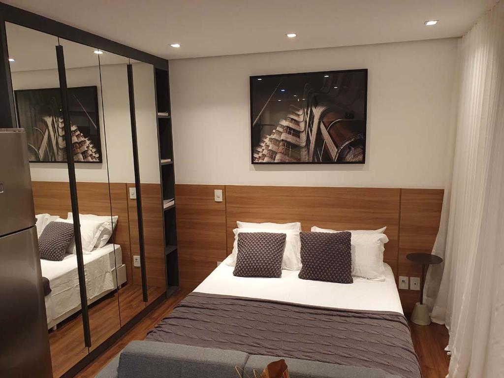 Schlafzimmer mit einem Bett und einem Spiegel in der Unterkunft Studio Aconchegante in São Paulo