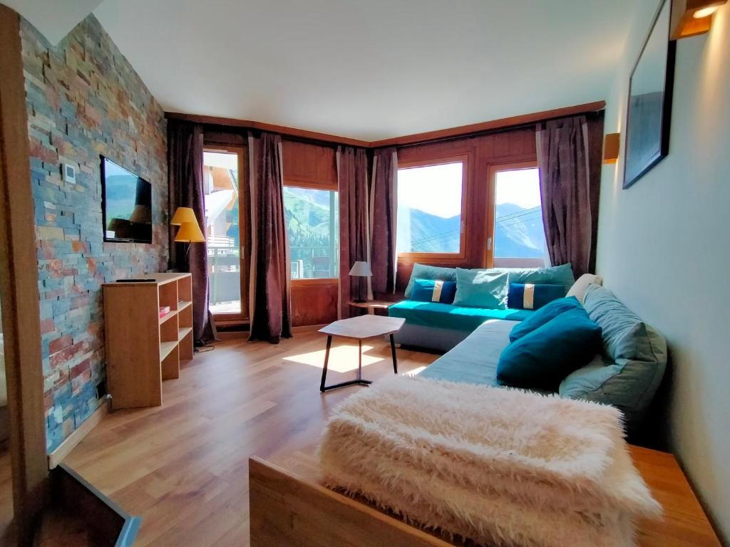- un salon avec un canapé bleu dans une pièce dotée de fenêtres dans l'établissement Avoriaz: Appartement cosy 3 pièces pour 5 pers avec WiFi, TV, appareil à raclette - FR-1-633-77, à Morzine