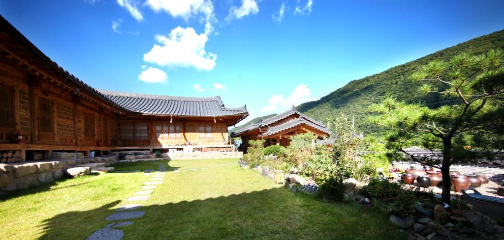 a building with a grass yard next to a mountain at Danyang Hanok 단양한옥가대리 in Danyang