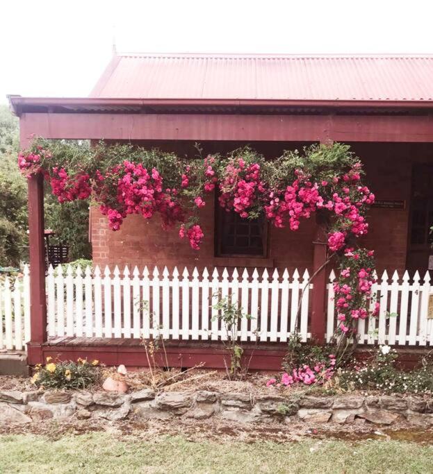 a white fence with pink flowers on a house at Historic Schoolhouse Rockley in Rockley
