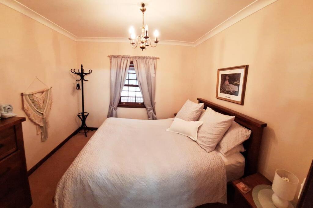 a bedroom with a bed with a chandelier and a window at Historic Schoolhouse Rockley in Rockley