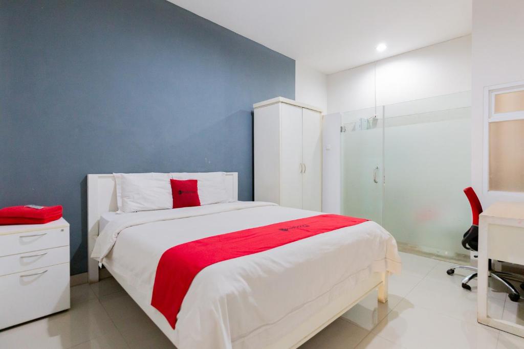 1 dormitorio con cama blanca y manta roja en RedDoorz Plus near Living Plaza Jababeka, en Bekasi