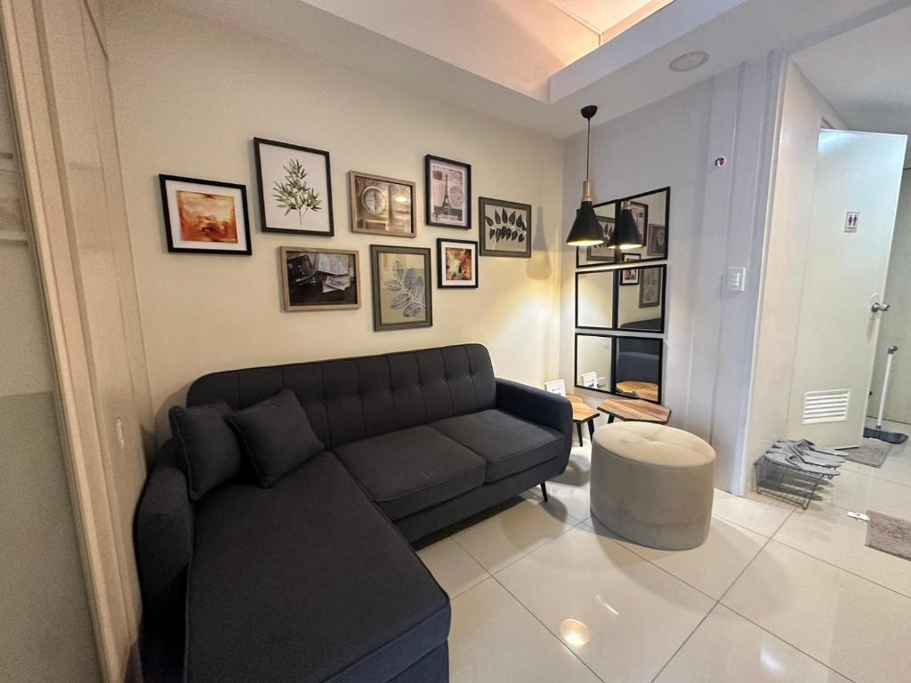 a living room with a black couch and pictures on the wall at Cozy 1 Bedroom in Makati City in Manila