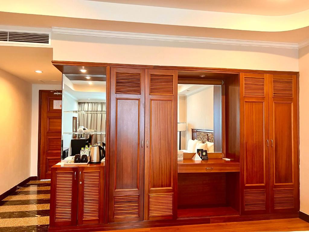 A full wall of wooden wardrobes with a mirrored dressing and beverage area.