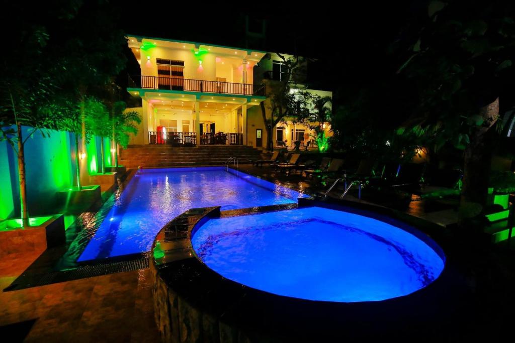 uma piscina com luzes azuis em frente a uma casa em Yala River Front Hotel & Restaurant em Tissamaharama