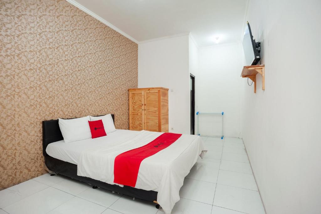 a bedroom with a bed with a red and white blanket at RedDoorz Syariah near Jatisampurna Hospital in Bekasi