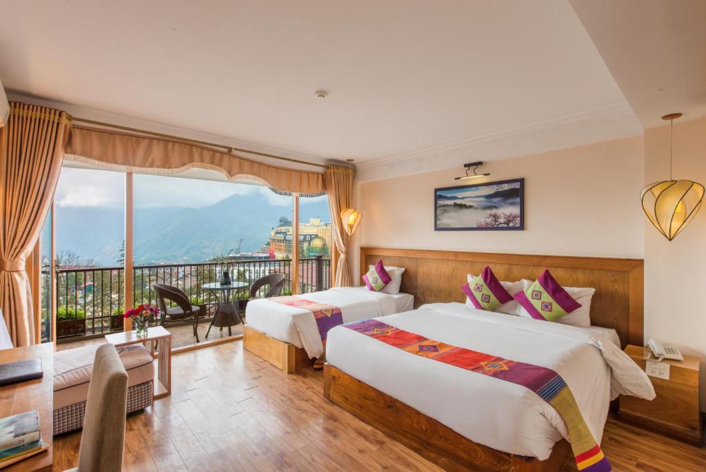 a hotel room with two beds and a balcony at Sapa Panorama Hotel in Sa Pa