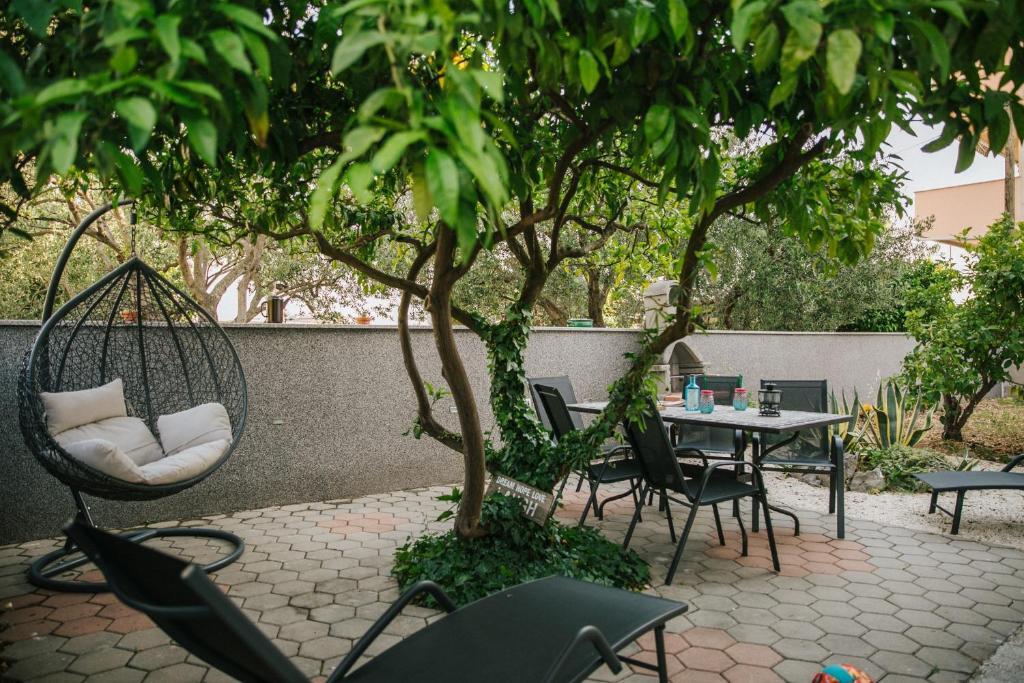 un patio con mesa, sillas y un árbol en Apartment Florio - garden & free parking, en Trogir