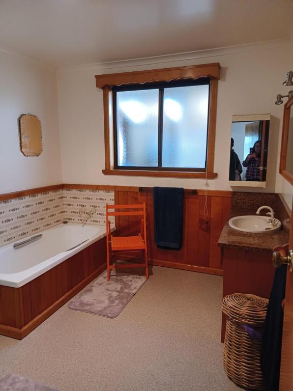 a bathroom with a tub and a chair and a sink at the tigers lair accomadation in Mole Creek