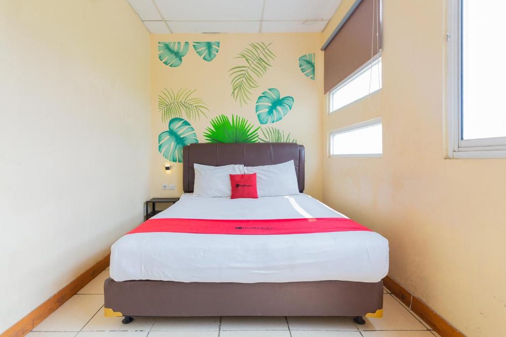 a bedroom with a large bed with a red pillow at RedDoorz @ Iodium Residence Cikarang in Jakarta