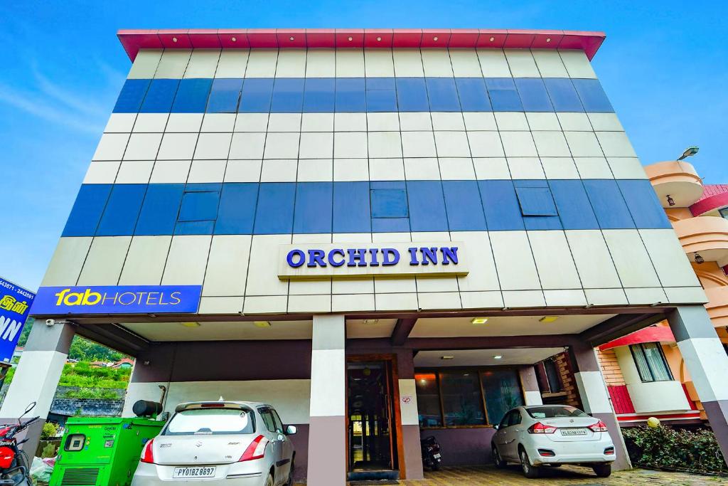 zwei Autos, die vor einem Hotel geparkt sind in der Unterkunft Hotel Orchid Inn in Udagamandalam