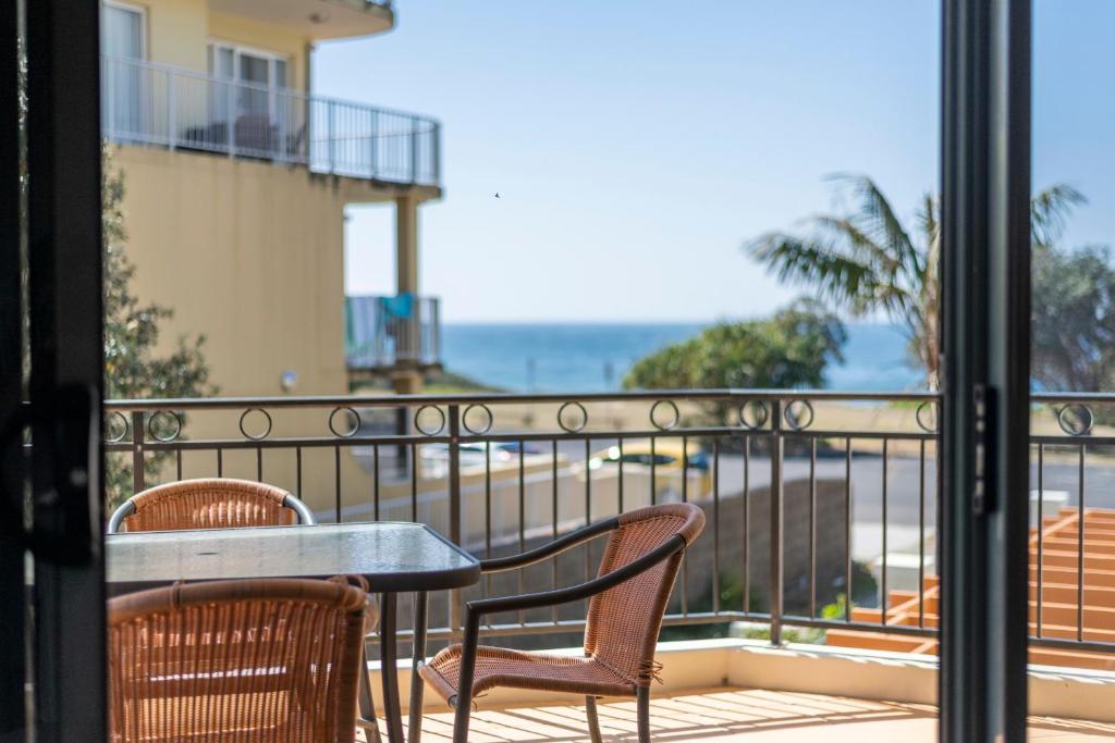 a table and chairs on a balcony with a view of the ocean at Breakers 1 8 LJHooker Yamba in Yamba