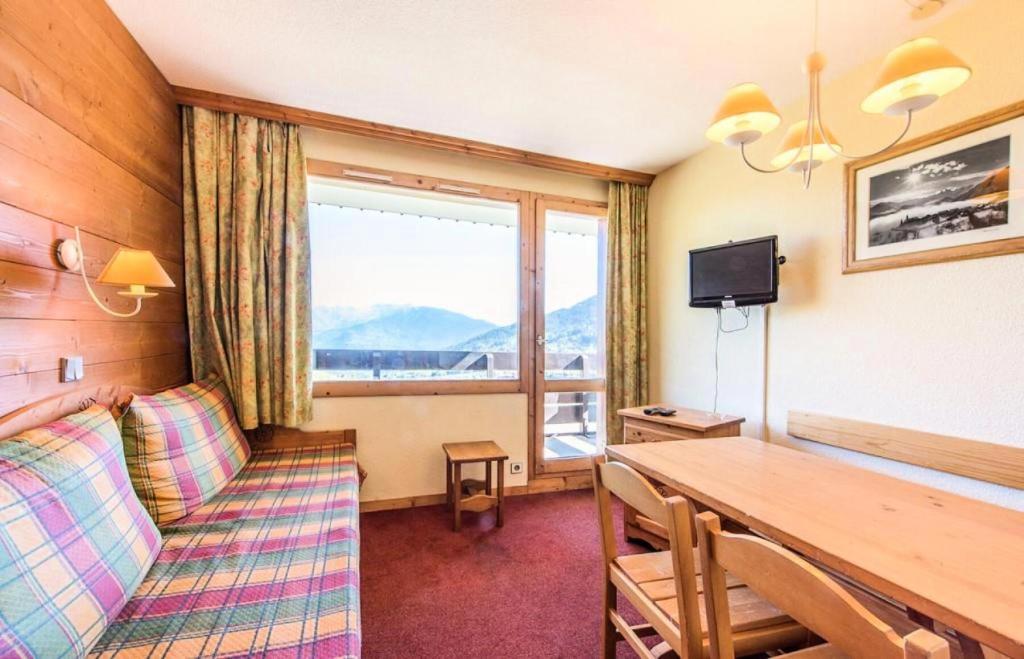 Cette chambre comprend une table, un canapé et une fenêtre. dans l'établissement Quartier La Forêt - maeva Home - 2 Pièces 5 Personnes Confort MAE-3074, à Valmorel