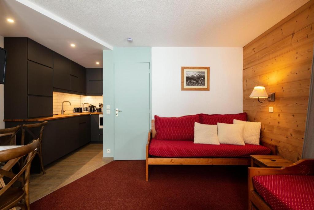 un salon avec un canapé rouge et une cuisine dans l'établissement Quartier Crève Cœur - maeva Home - 2 Pièces 5 personnes Selection MAE-3311, à Valmorel