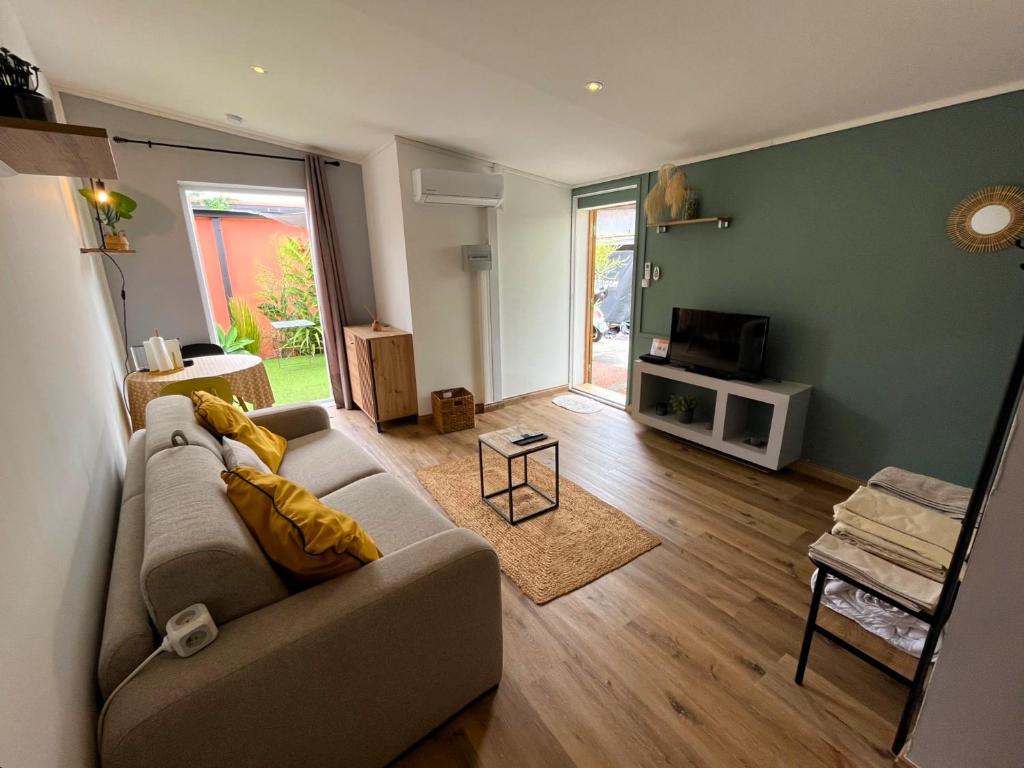 uma sala de estar com um sofá e uma televisão em Charmant bungalow climatisé avec jacuzzi em Sainte-Clotilde