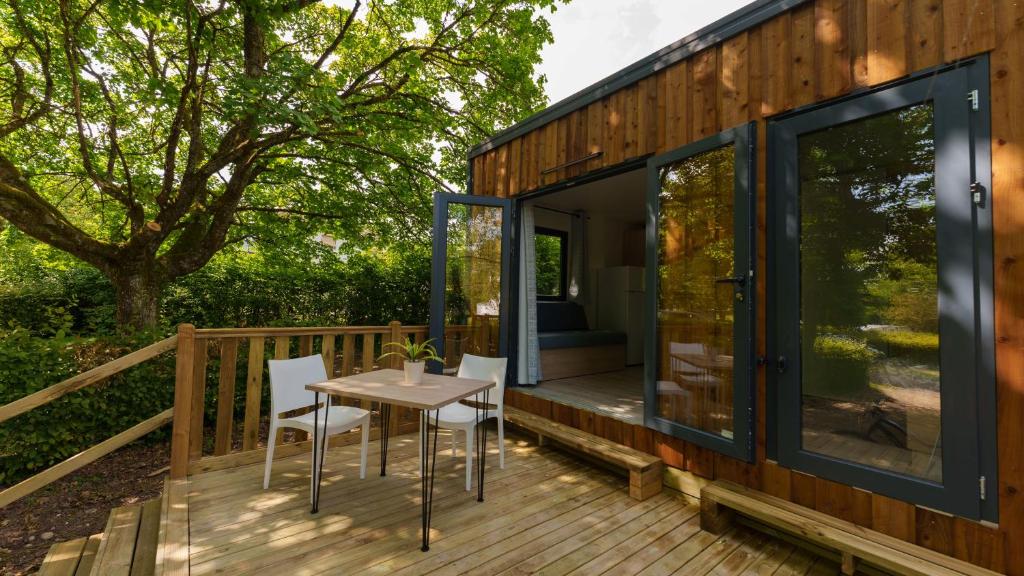 una casa con puertas de cristal y una mesa en una terraza en Camping Vittel, en Vittel