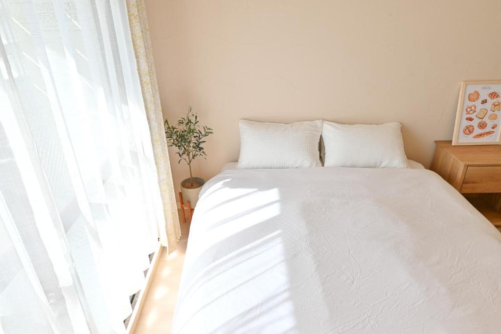 Un dormitorio con una cama con sábanas blancas y una ventana. en 小春日和_沖繩_松山館, en Naha