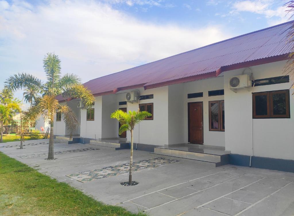 Home Syariah Guest House Ampana في Dondo: مبنى أبيض صغير بسقف أرجواني