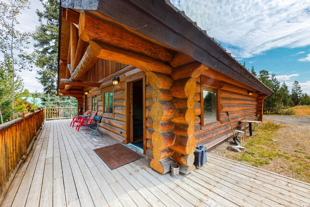 Cabaña de madera con porche y terraza con sillas. en Lac Le Jeune at Cabin 29 and 30, en Kamloops