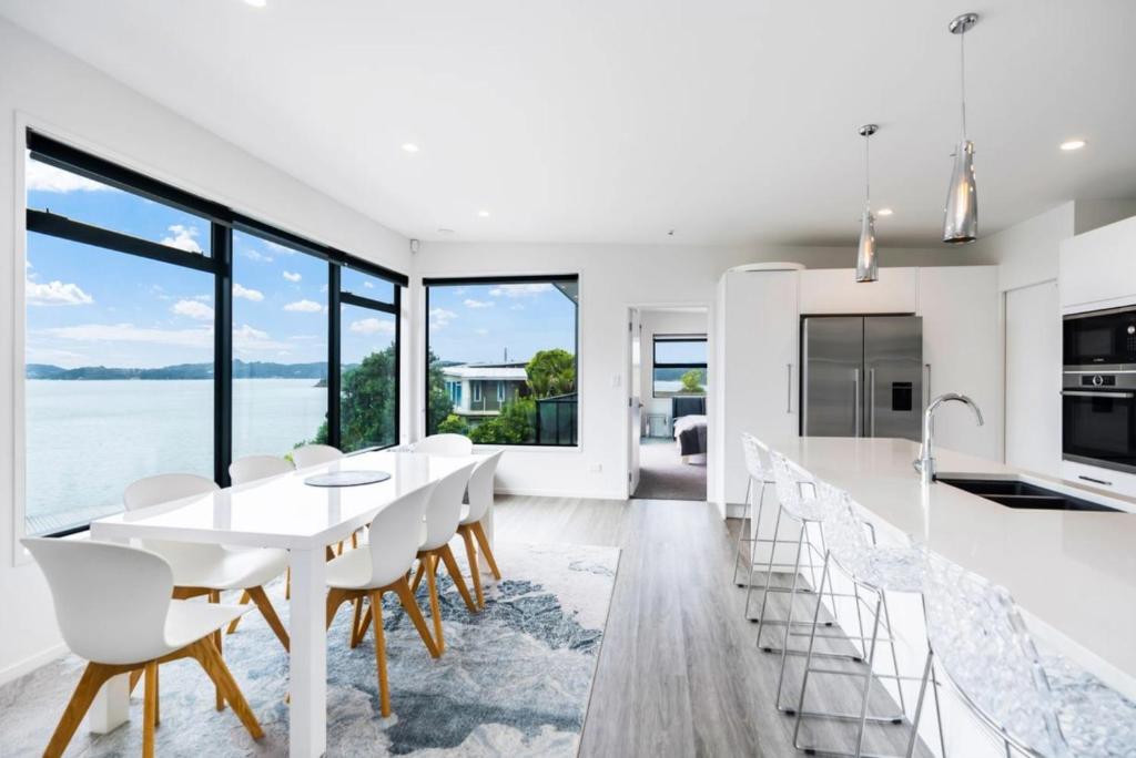 a kitchen and dining room with a white table and chairs at Bayview Apartment - Paihia Holiday Apartment in Paihia