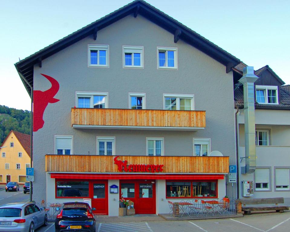 キプフェンベルクにあるGasthof Metzgerei Neumeyerの赤い看板が貼られた大きな建物
