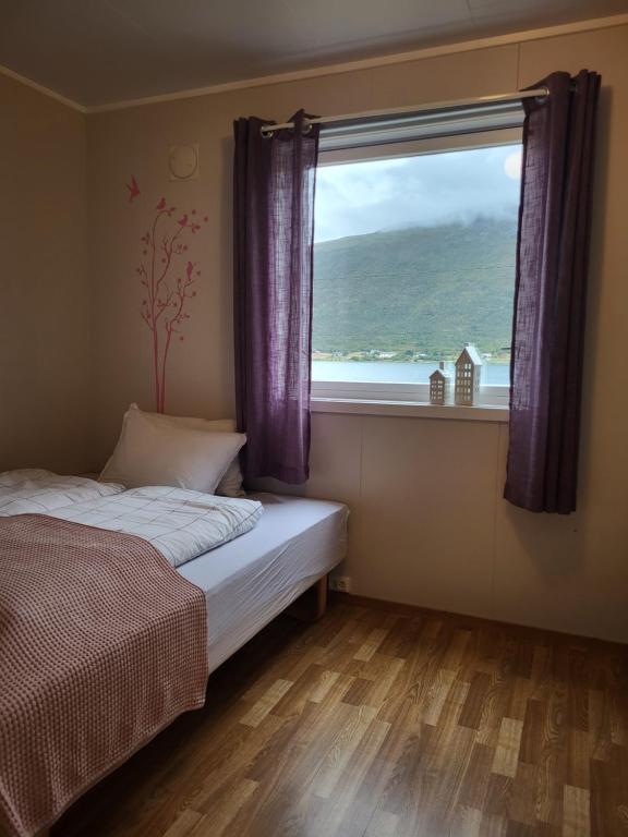 - une chambre avec un lit et une grande fenêtre dans l'établissement Idyllisk hus med sauna og jacuzzi, Lyngen, à Nord-Lenangen