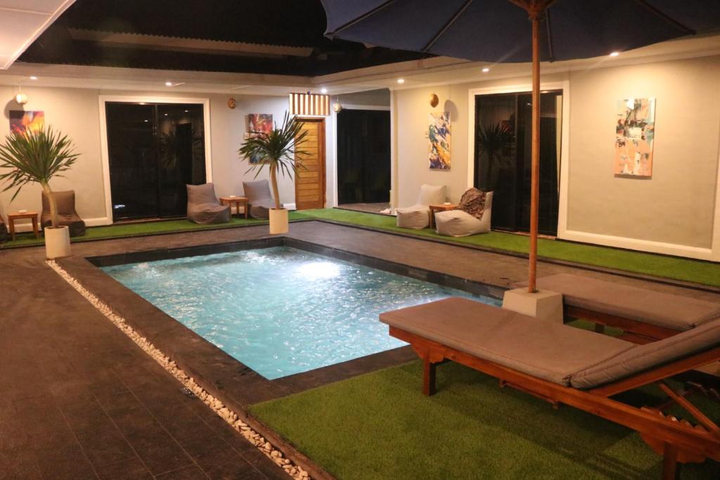 a swimming pool with an umbrella in a house at BALE DATU BUNGALLOW in Gili Trawangan