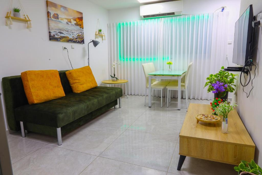 een woonkamer met een groene bank en een tafel bij דירת יהלום חדשה ומודרנית 5 דקות נסיעה מהים in Ashkelon