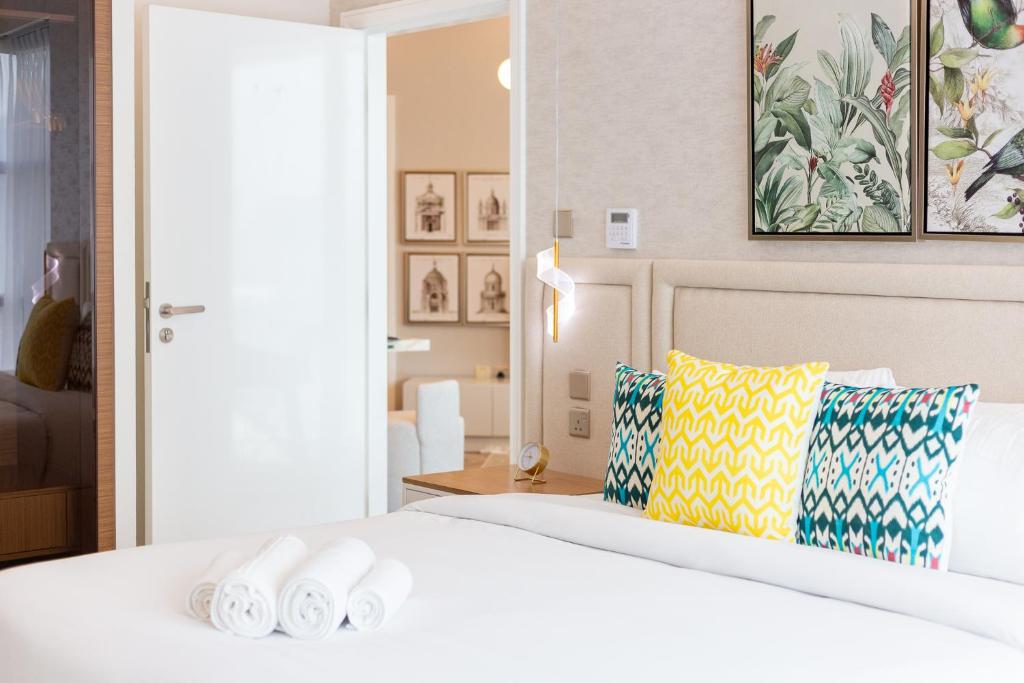 een slaapkamer met een groot wit bed met kussens bij Charming Brand New 2BR close to the Beach in Dubai